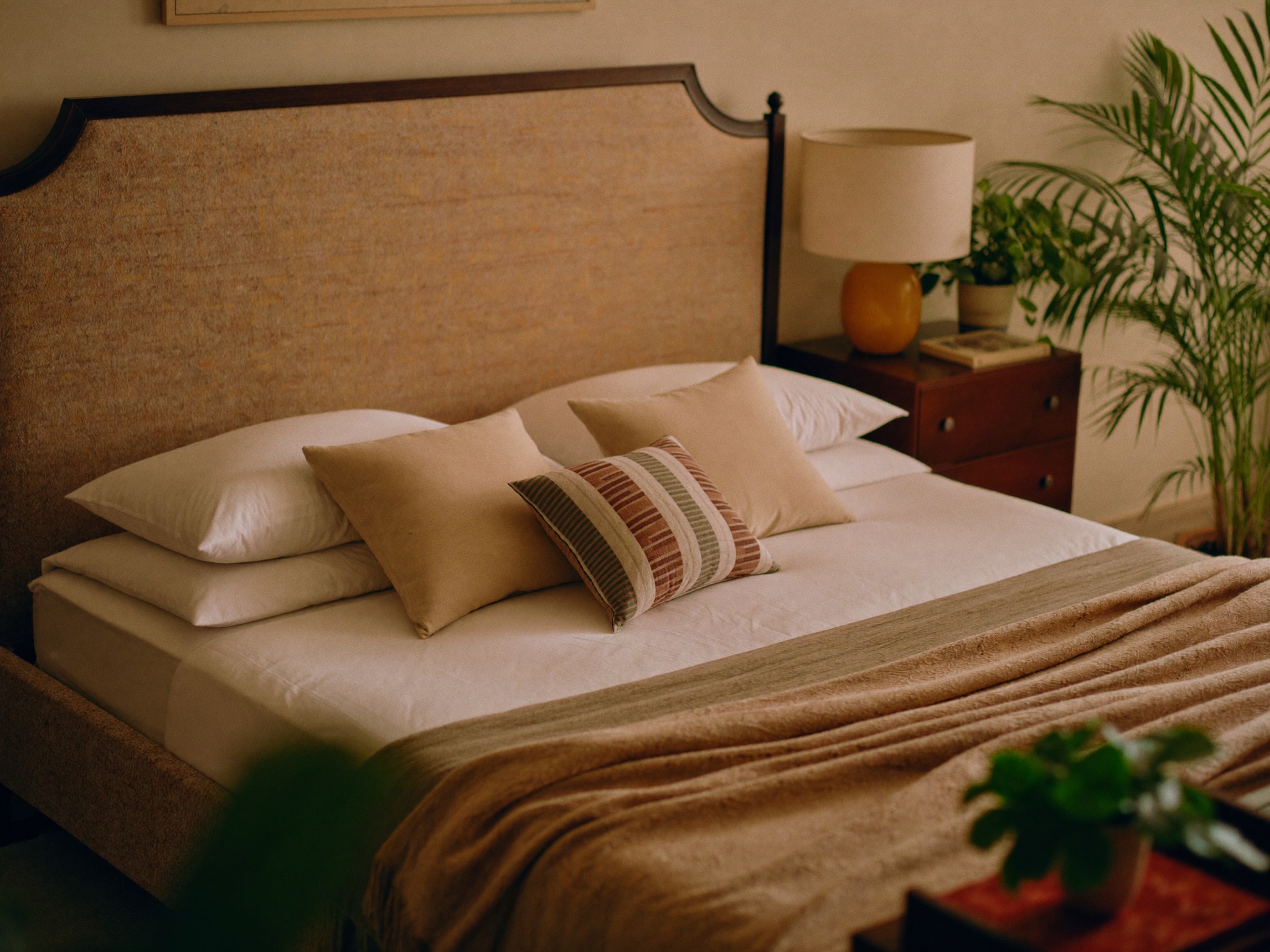 Made-up bed with fresh linens in a furnished private room with a nightstand and lamp